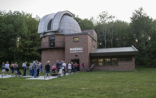 Nassau Astronomical Station — brick observatory with dome and a group gathered outside at dusk